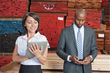 simsearch:693-06379747,k - Multiethnic business colleagues using tablet PC and cell phone with stacked wooden planks in background Stock Photo - Premium Royalty-Free, Code: 693-06379743