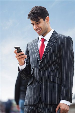 Happy Indian businessman using cell phone Foto de stock - Sin royalties Premium, Código: 693-06379822