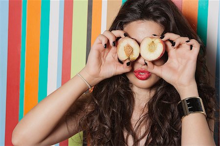 Young woman covering her eyes with peach against striped background Stock Photo - Premium Royalty-Free, Code: 693-06379841