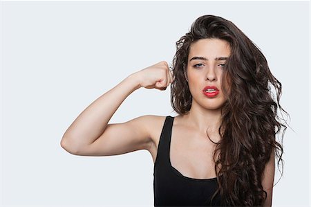 pune - Portrait of an aggressive woman with punching gesture over gray background Foto de stock - Sin royalties Premium, Código: 693-06379879