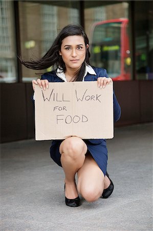 Young Indian businesswoman holding 'Will Work for Food' sign Stock Photo - Premium Royalty-Free, Code: 693-06379902