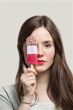 Portrait de jeune femme avec des lèvres rouges, tenant la barre de crème glacée sur fond gris Photographie de stock - Premium Libres de Droits, Code: 693-06380045