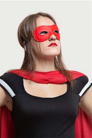 simsearch:693-06380036,k - Young woman in superhero costume looking up over gray background Foto de stock - Sin royalties Premium, Código: 693-06380084