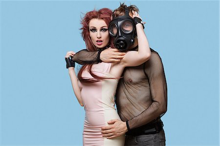 sassy - Portrait of young man wearing gas mask embraces funky woman over blue background Stock Photo - Premium Royalty-Free, Code: 693-06403223