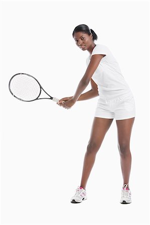 Portrait of young woman with tennis racket standing over white background Stock Photo - Premium Royalty-Free, Code: 693-06403319