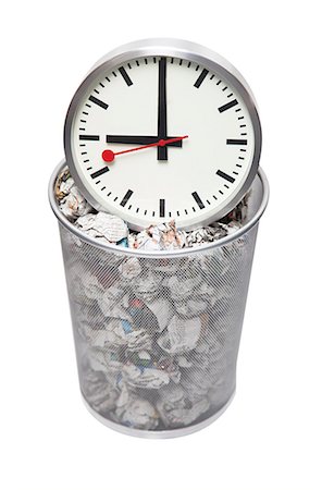 Clock in wastebasket full of crumpled paper over white background Stock Photo - Premium Royalty-Free, Code: 693-06403375