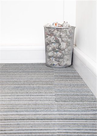 dustbin with waste material - Wastebasket full of crumpled paper in corner on carpet floor in room Stock Photo - Premium Royalty-Free, Code: 693-06403377