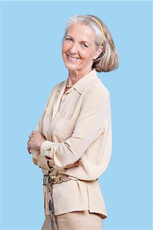 Portrait of smiling senior woman in casuals with arms crossed against blue background Stock Photo - Premium Royalty-Free, Code: 693-06403397