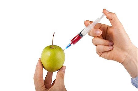 Man's hand injecting granny smith apple against white background Stock Photo - Premium Royalty-Free, Code: 693-06403392