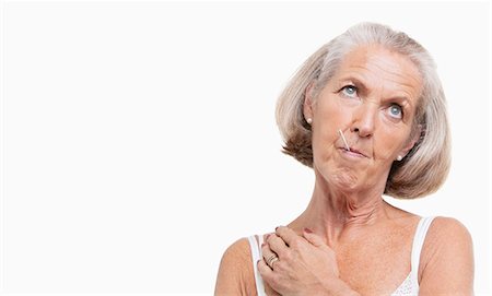 Unwell senior woman with thermometer in mouth against white background Stock Photo - Premium Royalty-Free, Code: 693-06403484