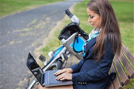 Young businesswoman using laptop while sitting on bench at park Stock Photo - Premium Royalty-Free, Code: 693-06403503