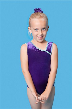 Portrait of a happy young female gymnast standing over blue background Stock Photo - Premium Royalty-Free, Code: 693-06403558