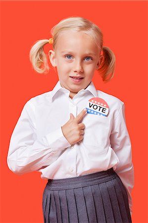 Portrait of a young school girl with vote badge over orange background Stock Photo - Premium Royalty-Free, Code: 693-06403589