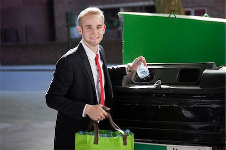Portrait of young businessman throwing plastic bottles in bin Stock Photo - Premium Royalty-Free, Code: 693-06435830