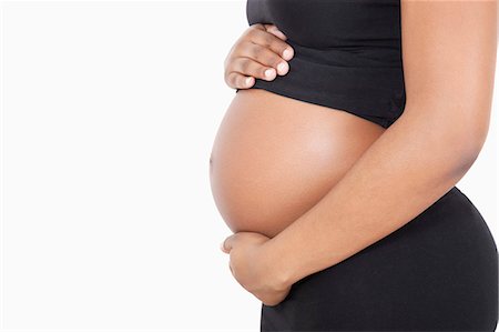 pregnant stomach - Mid section of young pregnant woman with hands on stomach over white background Stock Photo - Premium Royalty-Free, Code: 693-06435853