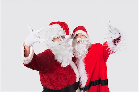 simsearch:693-06435898,k - Portrait of young men in Santa costume gesturing over gray background Stock Photo - Premium Royalty-Free, Code: 693-06435902