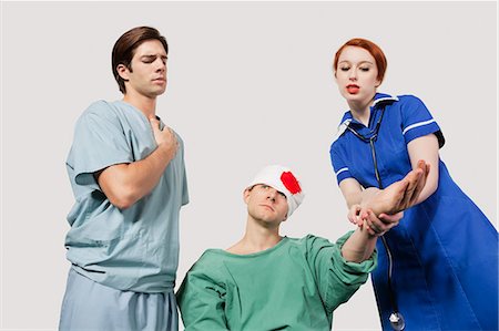 simsearch:693-06324311,k - Male doctor with female nurse treating an injured patient against gray background Stock Photo - Premium Royalty-Free, Code: 693-06435915