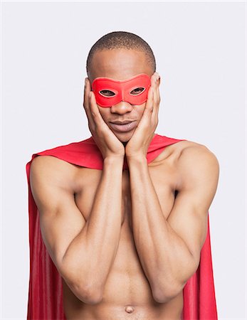 simsearch:693-06435933,k - Portrait of young shirtless man in superhero costume with hands on face against gray background Stock Photo - Premium Royalty-Free, Code: 693-06435942