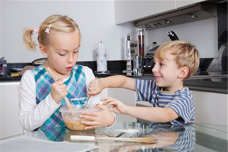 Happy brother and sister mixing batter together in kitchen Stock Photo - Premium Royalty-Free, Code: 693-06435981
