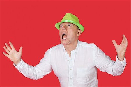 Portrait of an shocked man screaming against red background Stock Photo - Premium Royalty-Free, Code: 693-06436054