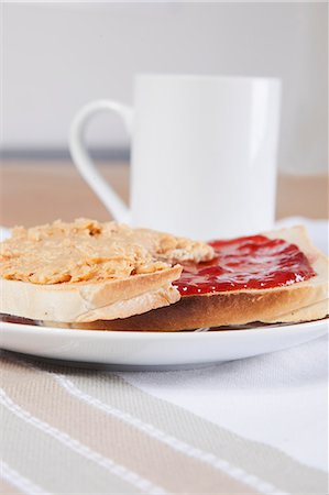 Peanut butter and jam on slices of bread with cup of coffee Stock Photo - Premium Royalty-Free, Code: 693-06497584