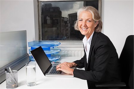 side view in chair - Portrait of smiling senior businesswoman using laptop at desk in office Stock Photo - Premium Royalty-Free, Code: 693-06497628