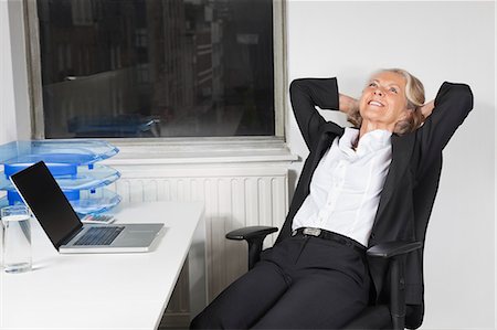 Smiling senior businesswoman relaxing at desk in office Stock Photo - Premium Royalty-Free, Code: 693-06497629