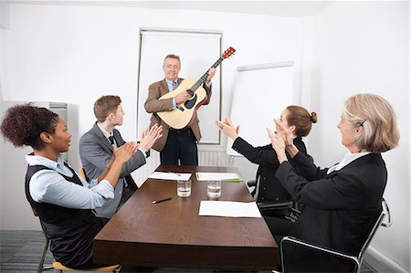 Businessman playing guitar in business meeting Stock Photo - Premium Royalty-Free, Code: 693-06497673