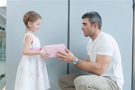 family city kid - Young girl handing present to her father Stock Photo - Premium Royalty-Free, Code: 693-06967389