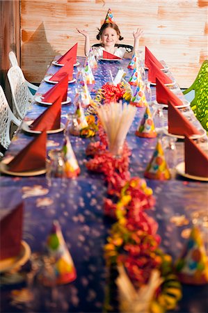 Happy young girl at her dinner party table wearing party hat Stock Photo - Premium Royalty-Free, Code: 693-06967399