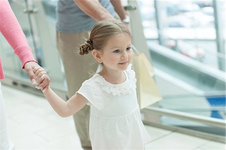 parents children shopping - Close-up of young girl holding parents hands Stock Photo - Premium Royalty-Free, Code: 693-06967410