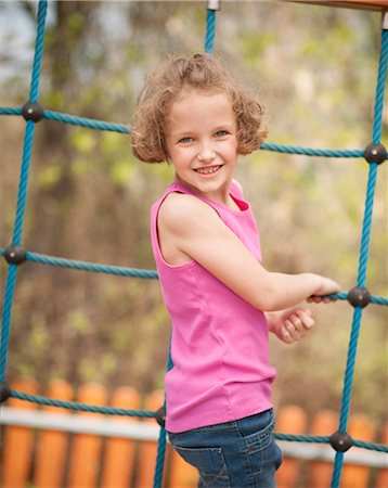 Young girl on climbing net turning to face camera Stock Photo - Premium Royalty-Free, Code: 693-06967455