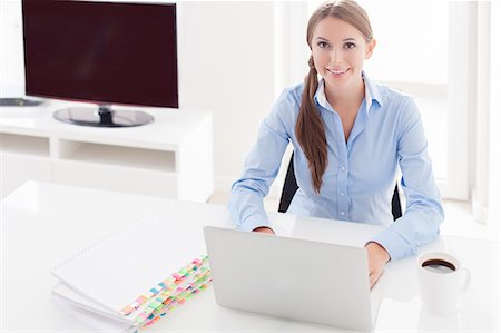 Businesswoman looking bored in front of laptop and television Stock Photo - Premium Royalty-Free, Code: 693-07444411