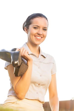 Portrait of happy young businesswoman holding high heels against sky Stock Photo - Premium Royalty-Free, Code: 693-07444470