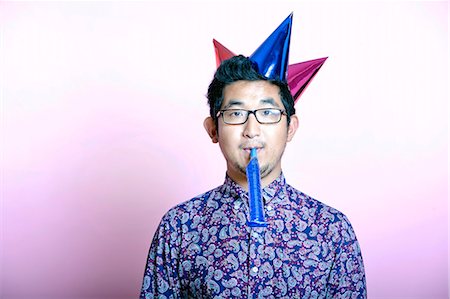 Young Geeky Asian Man wearing many party hats Stock Photo - Premium Royalty-Free, Code: 693-07444533