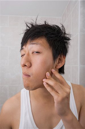 pimple - Asian mid adult man examining his face in bathroom Stock Photo - Premium Royalty-Free, Code: 693-07455934