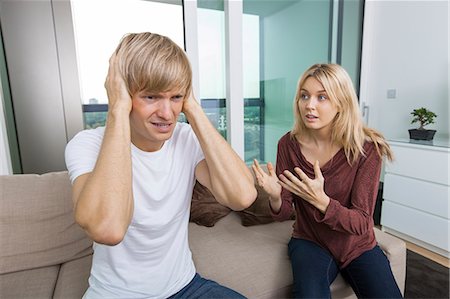 Woman trying to talk as man yells out aloud in living room at home Photographie de stock - Premium Libres de Droits, Code: 693-07456056