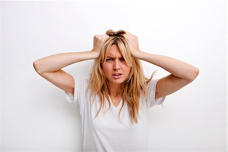 Portrait of frustrated woman pulling against white background Stock Photo - Premium Royalty-Free, Code: 693-07456110
