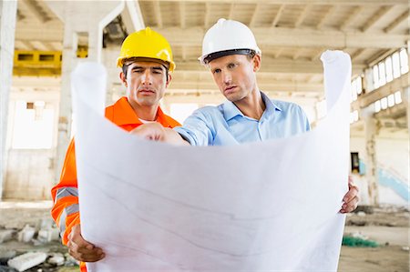 Male architects discussing over blueprint at construction site Stock Photo - Premium Royalty-Free, Code: 693-07456129
