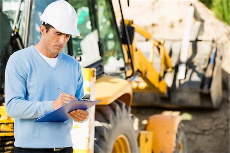 Male architect writing on clipboard against earthmover at construction site Stock Photo - Premium Royalty-Free, Code: 693-07456140