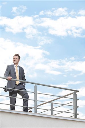 railing - Young businessman standing at terrace railings against sky Photographie de stock - Premium Libres de Droits, Code: 693-07456188