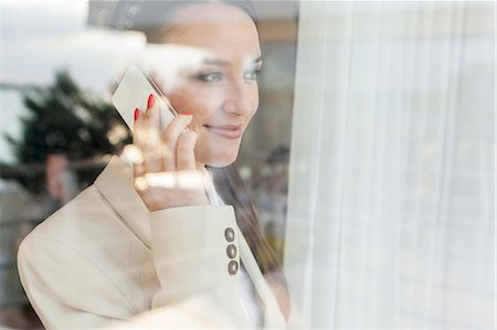 Young businesswoman using cell phone in office Stock Photo - Premium Royalty-Free, Code: 693-07456272