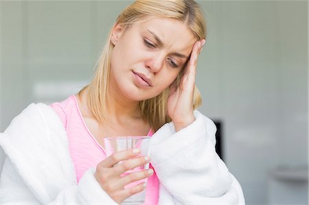 simsearch:693-07456416,k - Young woman suffering from headache while holding glass of water Foto de stock - Sin royalties Premium, Código: 693-07456355