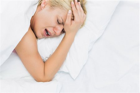 simsearch:693-07456416,k - Young woman screaming while suffering from headache in bed Foto de stock - Sin royalties Premium, Código: 693-07456362