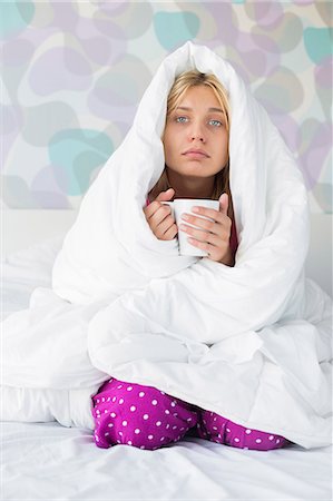simsearch:693-07456416,k - Portrait of young woman with coffee mug suffering from fever while wrapped in quilt on bed Foto de stock - Sin royalties Premium, Código: 693-07456379