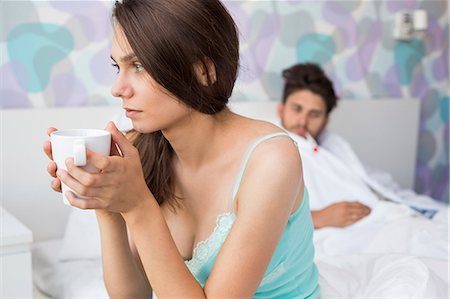 simsearch:693-07456416,k - Worried young woman holding coffee mug while ill man relaxing in background Foto de stock - Sin royalties Premium, Código: 693-07456391