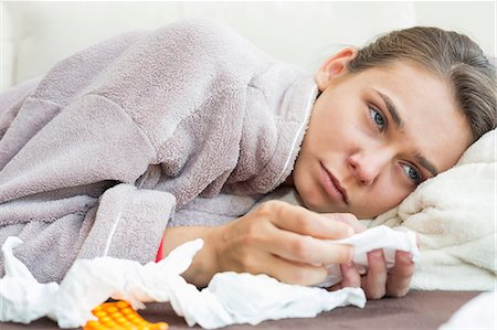 flu - Sick woman with tissue and medicines lying on bed Stock Photo - Premium Royalty-Free, Code: 693-07456401