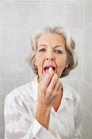 Portrait of senior woman applying lipstick in bathroom Stock Photo - Premium Royalty-Free, Code: 693-07456455