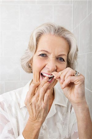 dental floss - Portrait of senior woman flossing teeth in bathroom Stock Photo - Premium Royalty-Free, Code: 693-07456451