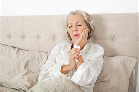 sickness - Senior woman suffering from toothache resting in bed Stock Photo - Premium Royalty-Free, Code: 693-07456461